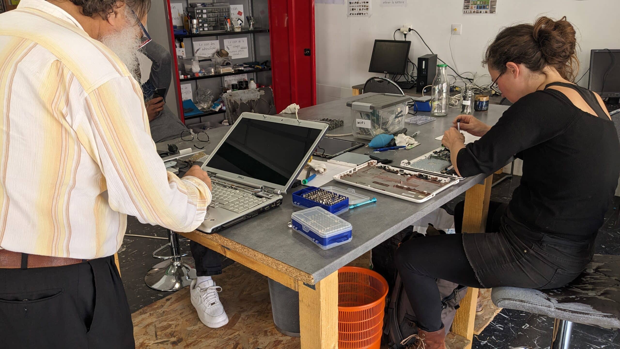 photo atelier d'auto-réparation : deux personnes démontent des ordinateurs portables